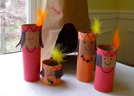Bonecos feitos com rolos de papel, representando figuras indígenas, com adornos coloridos.