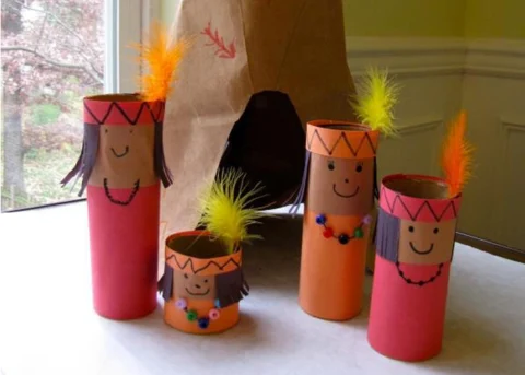 Bonecos feitos com rolos de papel, representando figuras indígenas, com adornos coloridos.
