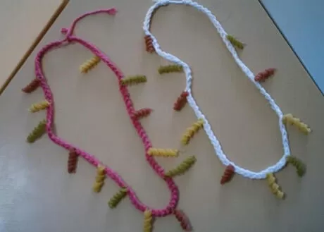 Colares feitos de fios coloridos com detalhes em formato de pequenos pompons.