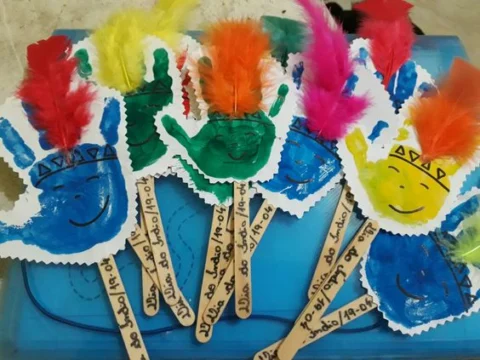 Mãos coloridas com penas em um fundo azul.